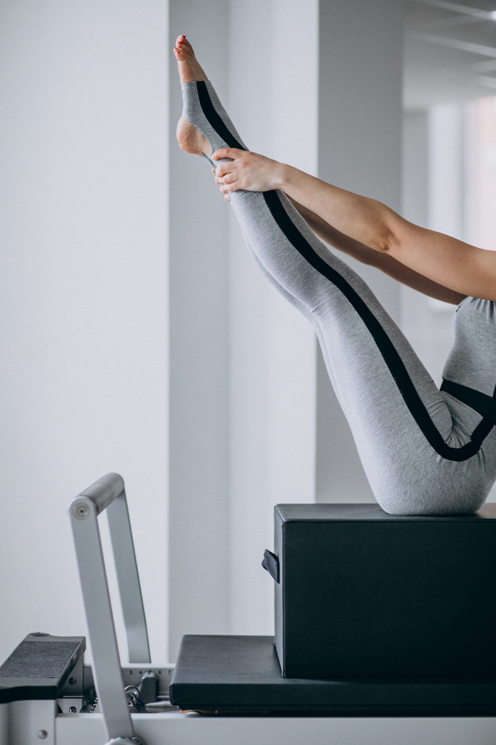 Woman practising pilates in a pilates reformer legs close up